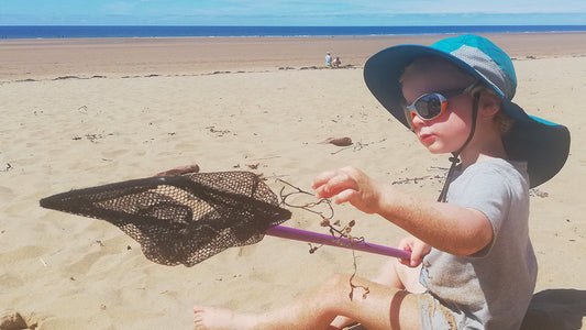 Toddler on the beach wearing a sun hat